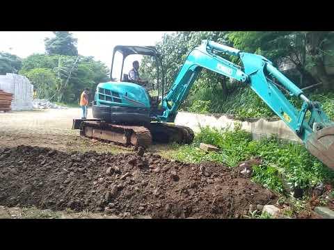 beko ngeruk tanah buat jalur air pembuangan - Pekerja Bangunan thumbnail